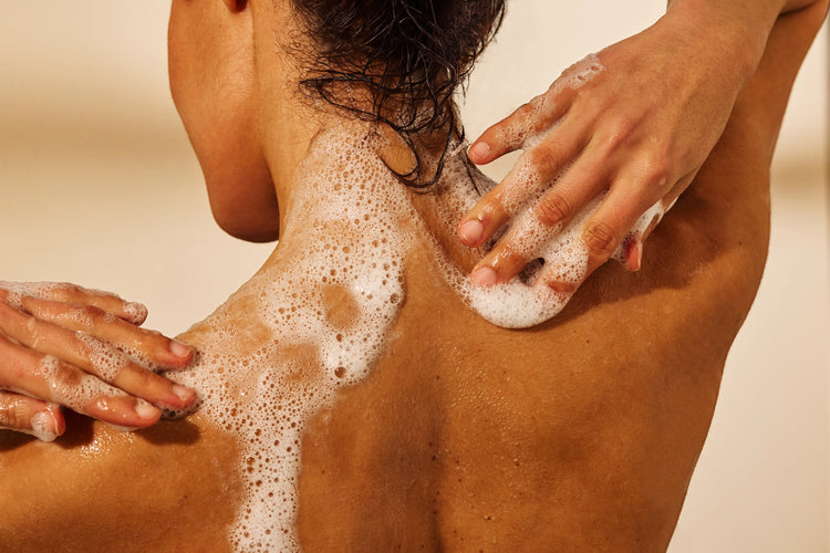 femme se lavant le corps avec un gel douche